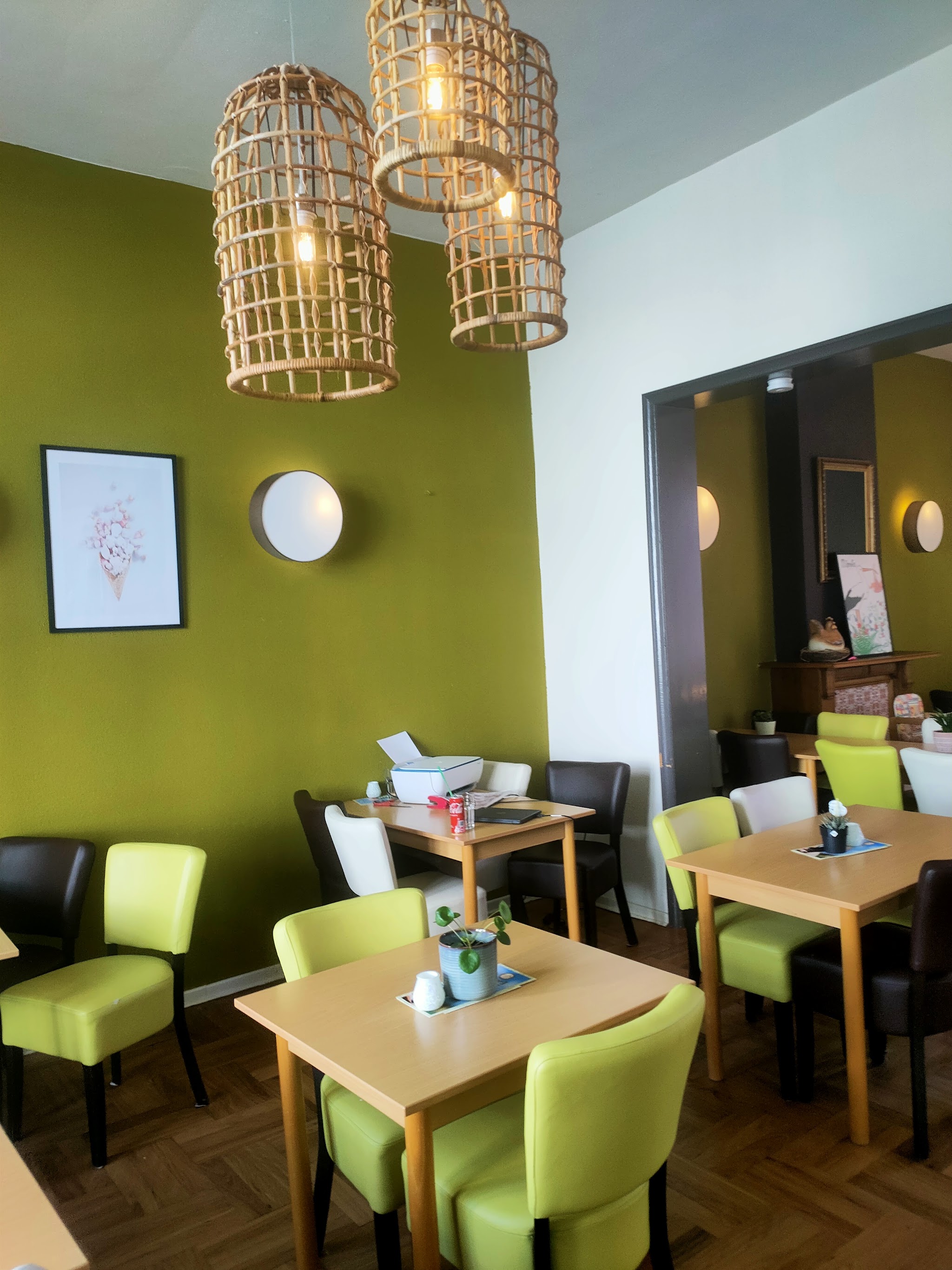 Binnen in de salon: mosgroene wand, rotan hanglampen en limoengroene stoelen