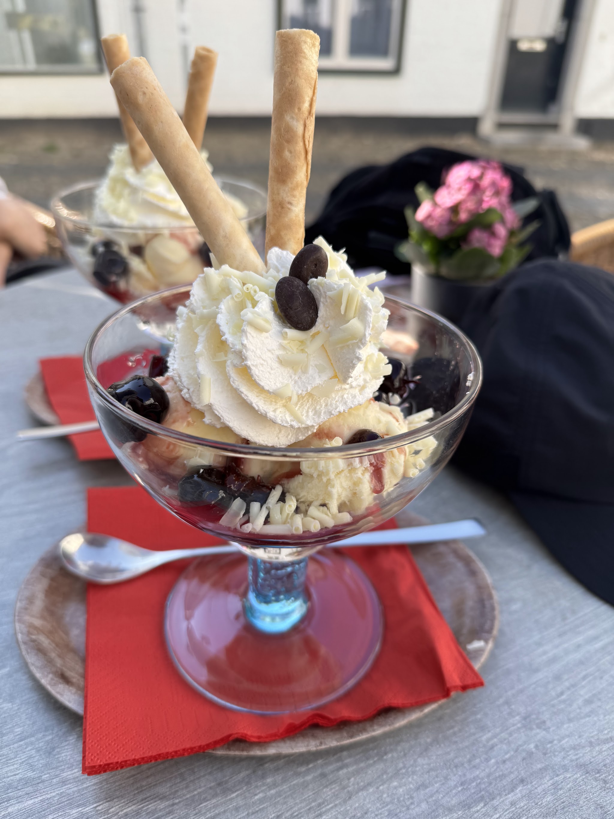 Een ijscoupe met amarenakersen, witte chocoladekrullen en wafelrolletjes