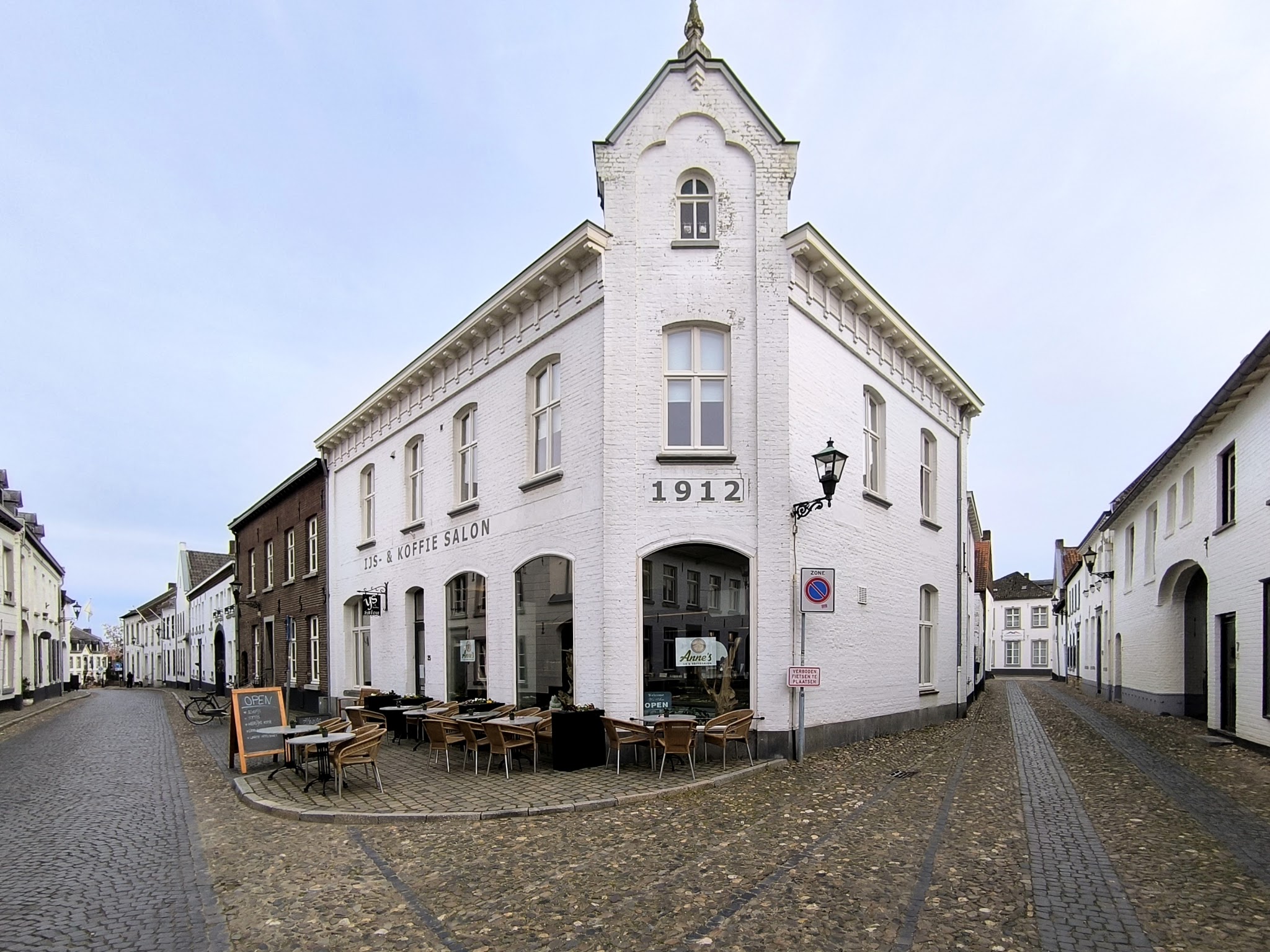 Het witte hoekpand van Anne's IJS- en Koffiesalon aan de Hoogstraat in Thorn, met het terras ervoor